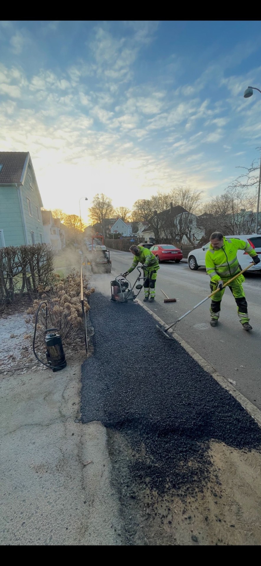 Handläggning av asfalt på villagata i morgonsol, Göteborg