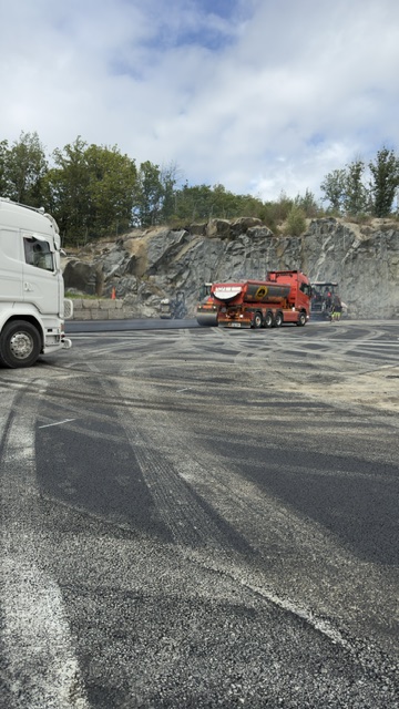 Scania-lastbil och asfaltläggare i arbete på stor entreprenad