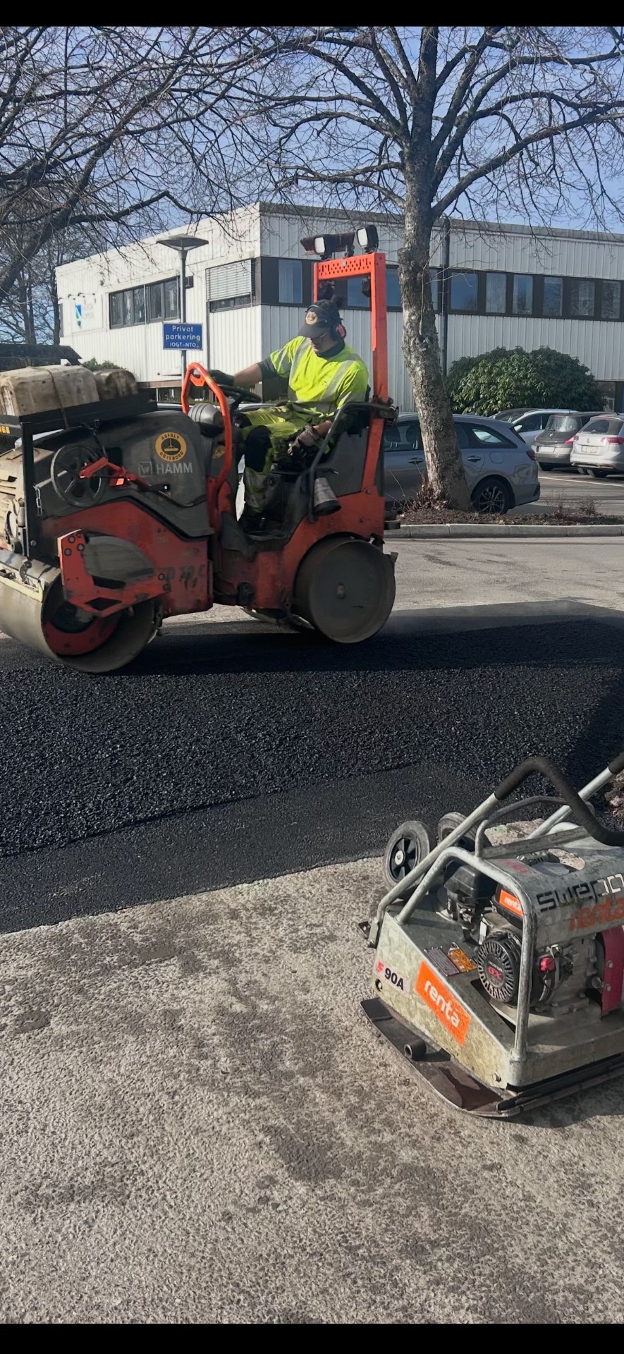 Vält jämnar ny asfalt på parkering vid kontor
