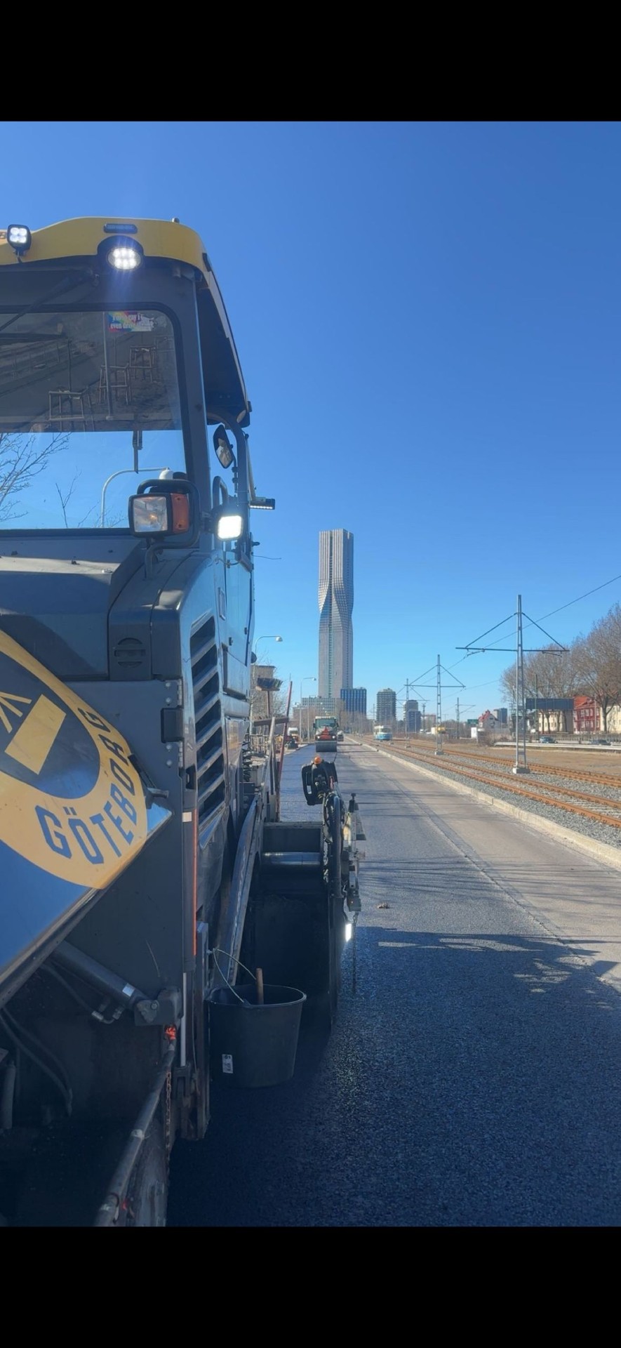 Asfaltering längs spårvagnsspår med Göteborgs skyline i bakgrunden