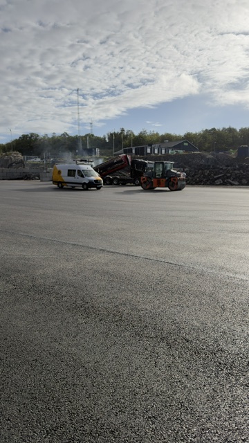 Servicebil på nyasfalterad storyta under öppen himmel